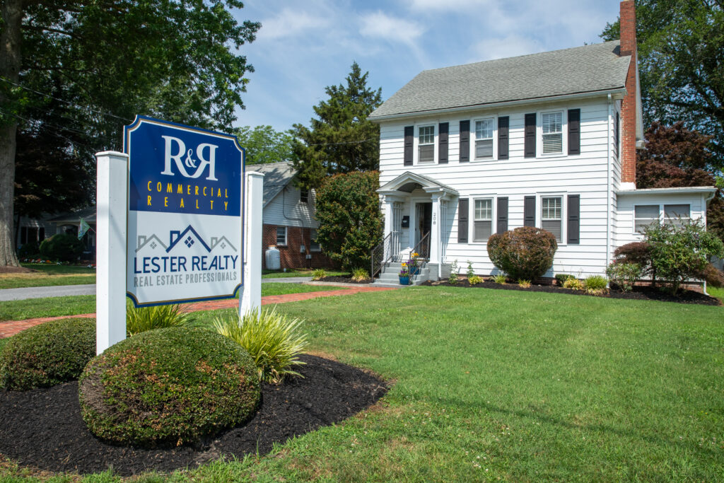 Exterior view of the R&R Commercial Realty office with the sign prominently displayed out front, surrounded by clean landscaping and a bright, welcoming entrance.